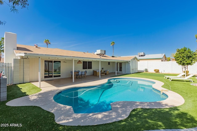 rear view of property featuring a fenced backyard, a yard, a chimney, and a patio