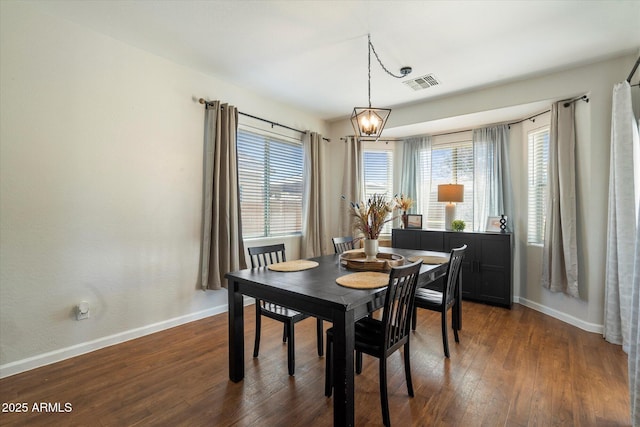 dining space with baseboards, dark wood-style flooring, visible vents, and a notable chandelier