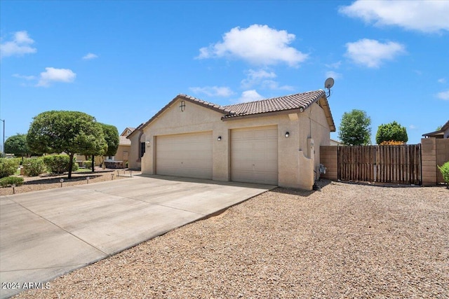 exterior space with concrete driveway, stucco siding, fence, a tiled roof, and a garage