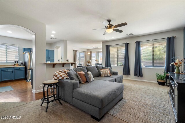 living room featuring visible vents, baseboards, recessed lighting, a ceiling fan, and arched walkways
