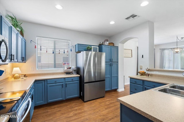 kitchen featuring blue cabinets, visible vents, a sink, and freestanding refrigerator