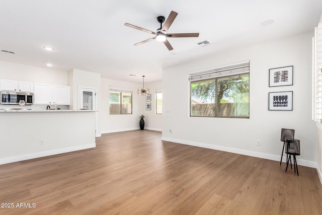 11891 N 147th Dr, Surprise, AZ 85379 - unfurnished living room featuring a wealth of natural light, light wood-style flooring, visible vents, and ceiling fan with notable chandelier