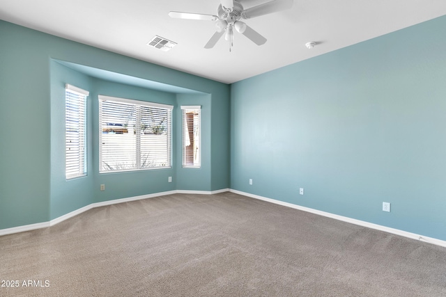 empty room with ceiling fan, carpet flooring, visible vents, and baseboards