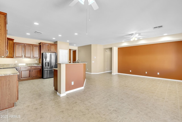 kitchen with recessed lighting, visible vents, a kitchen island with sink, ceiling fan, and stainless steel fridge