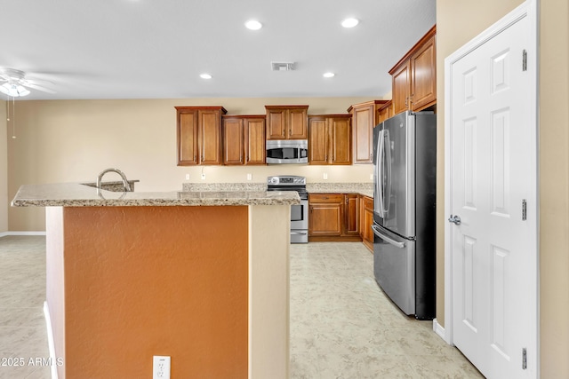 kitchen featuring visible vents, appliances with stainless steel finishes, brown cabinets, a center island, and recessed lighting