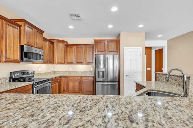 kitchen featuring light stone counters, recessed lighting, visible vents, appliances with stainless steel finishes, and a sink