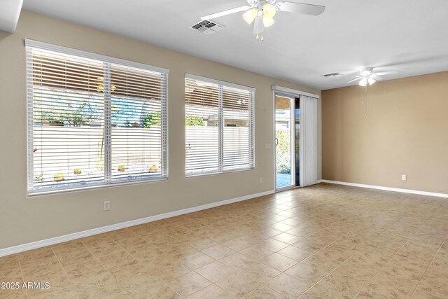 spare room featuring ceiling fan, visible vents, and baseboards