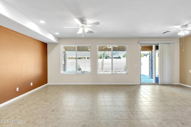 spare room with ceiling fan, light tile patterned floors, visible vents, and baseboards