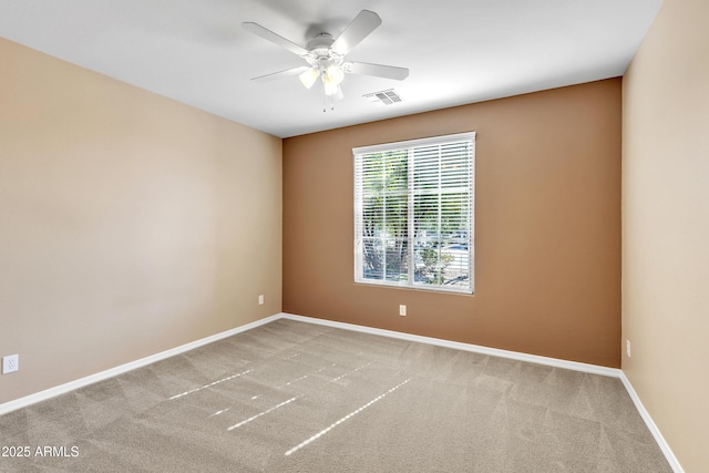 carpeted spare room featuring a ceiling fan, visible vents, and baseboards