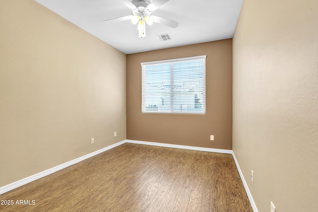 unfurnished room featuring a ceiling fan, visible vents, baseboards, and wood finished floors