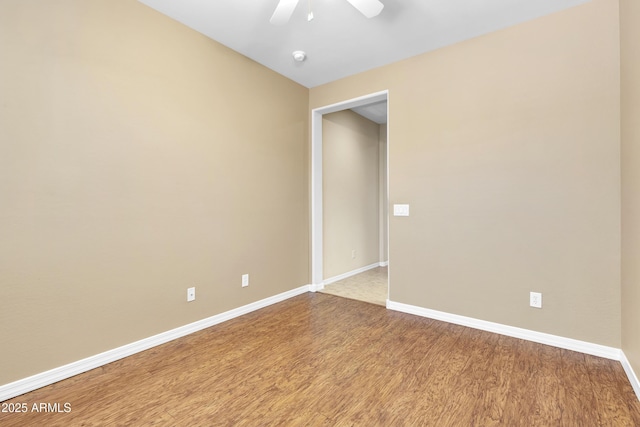 spare room with wood finished floors, a ceiling fan, and baseboards