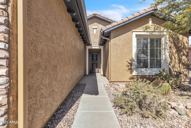 entrance to property with a tile roof and stucco siding