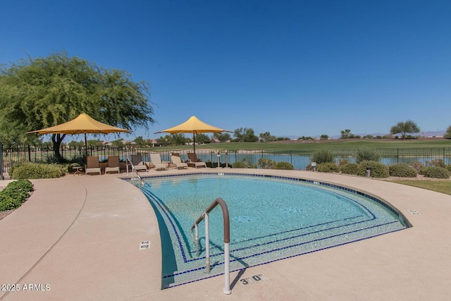 pool featuring a patio area, a water view, and fence