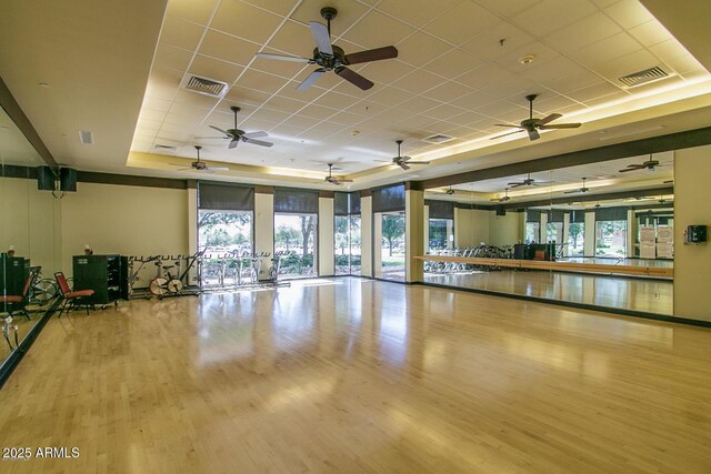 exercise area with a paneled ceiling, visible vents, a raised ceiling, and wood finished floors