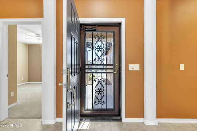 carpeted foyer featuring a ceiling fan and baseboards