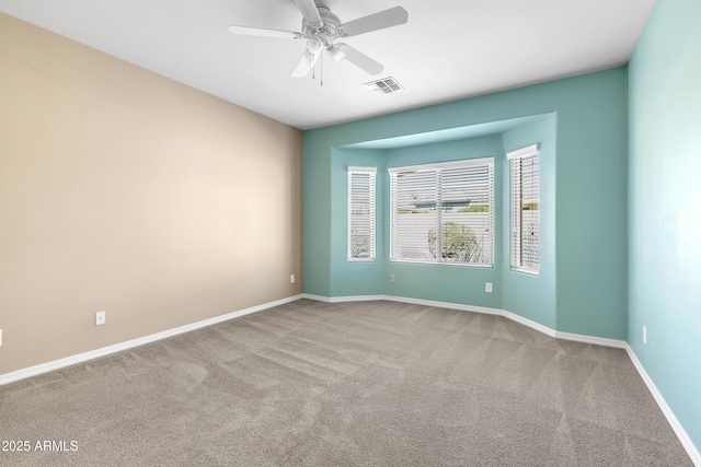 carpeted spare room with ceiling fan, visible vents, and baseboards