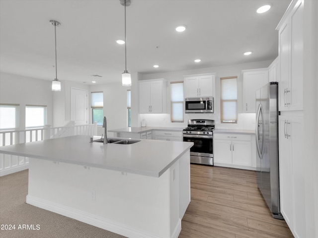 kitchen with sink, decorative light fixtures, white cabinets, and appliances with stainless steel finishes