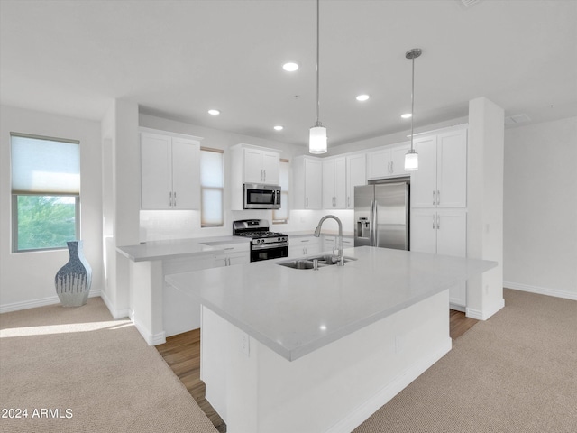 kitchen featuring an island with sink, appliances with stainless steel finishes, sink, and white cabinets