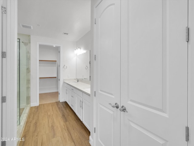 bathroom with wood-type flooring, vanity, and a shower with shower door