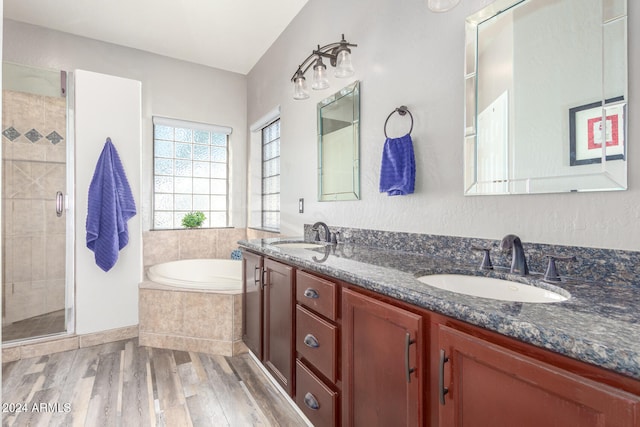 bathroom with plus walk in shower, hardwood / wood-style flooring, and vanity