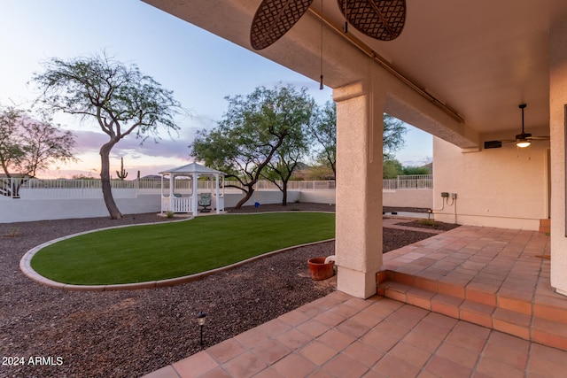 patio terrace at dusk featuring a gazebo and a yard