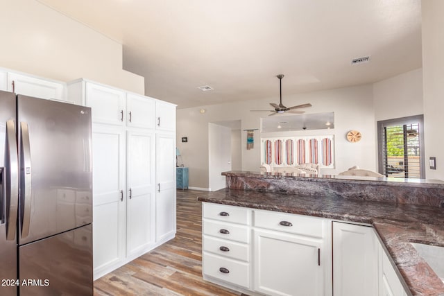 kitchen with light hardwood / wood-style flooring, dark stone countertops, white cabinets, and stainless steel fridge