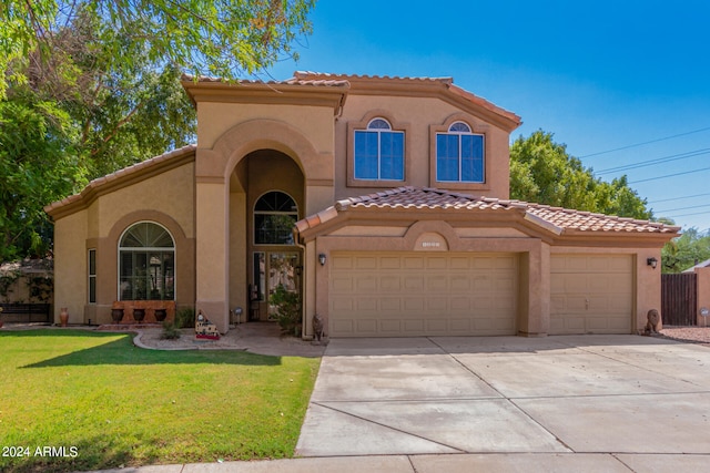 mediterranean / spanish home featuring a garage and a front yard