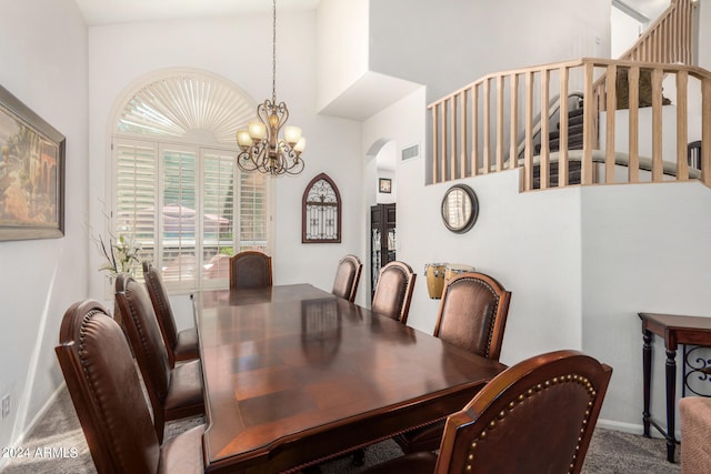 carpeted dining room with a chandelier and a towering ceiling