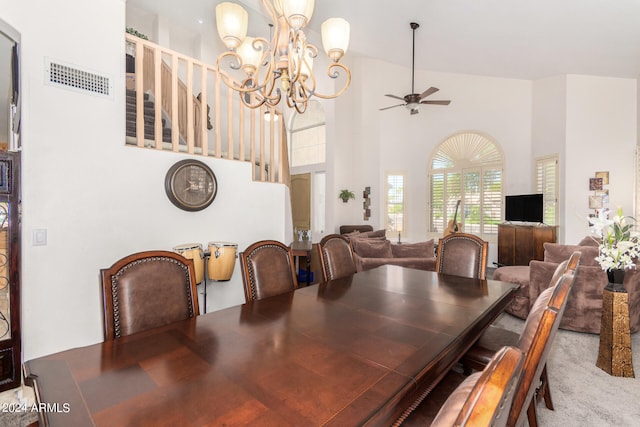 dining space featuring a high ceiling and ceiling fan with notable chandelier