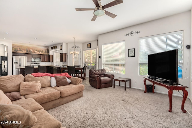 living room with ceiling fan with notable chandelier and light carpet