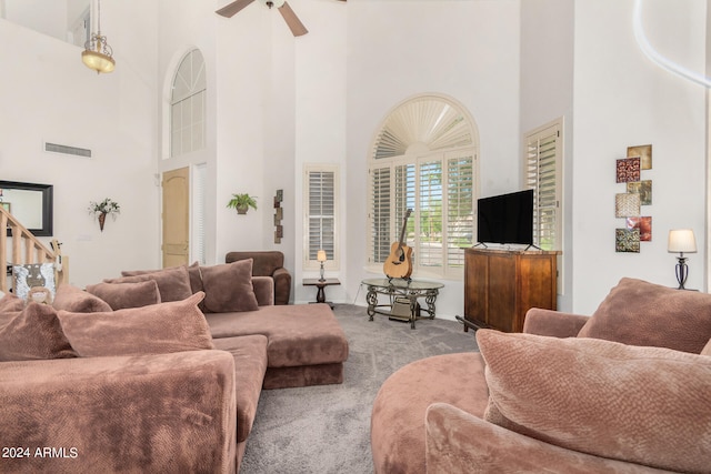 carpeted living room featuring ceiling fan and a towering ceiling