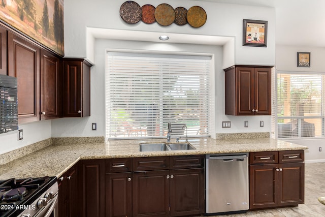 kitchen featuring stainless steel appliances, sink, light stone countertops, and dark brown cabinets