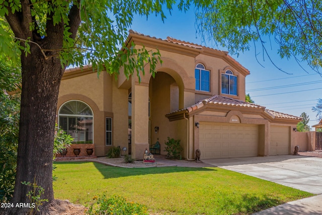 mediterranean / spanish home featuring a front yard and a garage