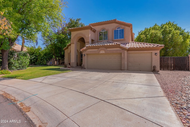 mediterranean / spanish-style home featuring a garage and a front lawn