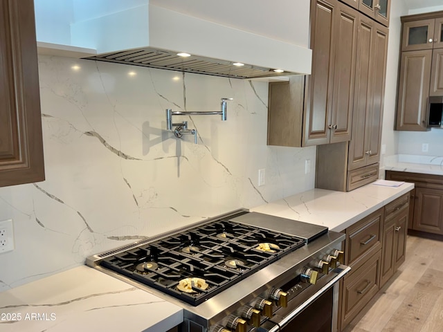3021 N 47th St, Phoenix, AZ 85018 - kitchen with stainless steel range, custom exhaust hood, glass insert cabinets, backsplash, and light stone counters