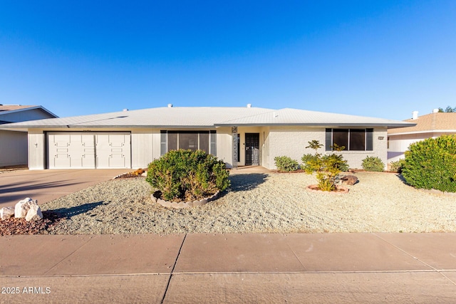 single story home featuring concrete driveway, an attached garage, and brick siding