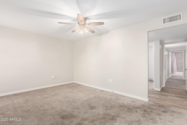 carpeted empty room featuring visible vents, ceiling fan, and baseboards