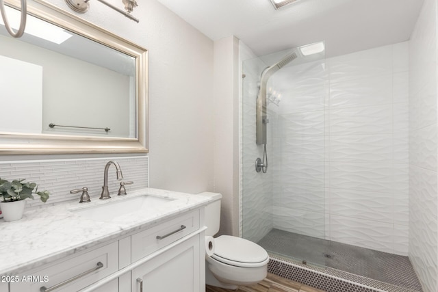 bathroom featuring tasteful backsplash, vanity, toilet, and a shower with door