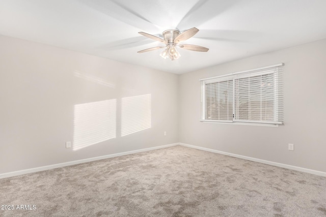 carpeted spare room with a ceiling fan and baseboards