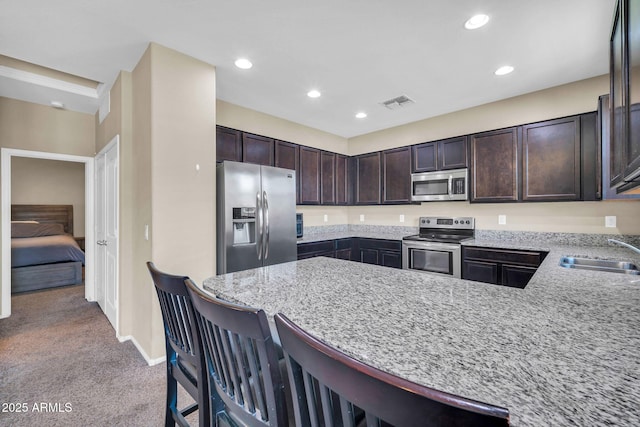 2049 N 77th Dr, Phoenix, AZ 85035 - kitchen featuring visible vents, appliances with stainless steel finishes, dark brown cabinets, a sink, and a peninsula