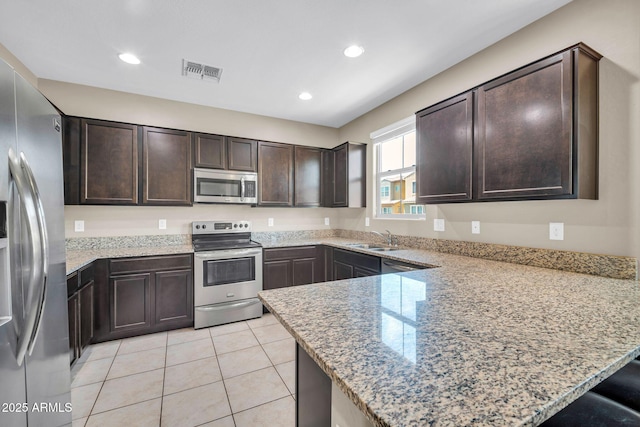 2049 N 77th Dr, Phoenix, AZ 85035 - kitchen featuring visible vents, appliances with stainless steel finishes, dark brown cabinets, a sink, and a peninsula