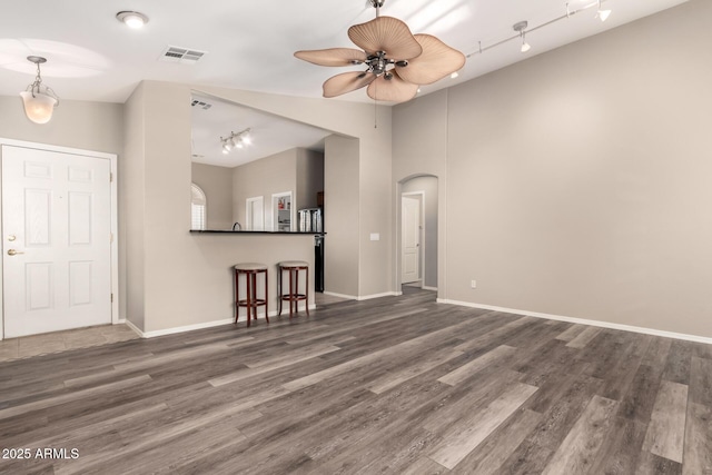 unfurnished living room with ceiling fan, rail lighting, and hardwood / wood-style floors