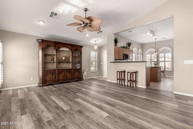 unfurnished living room with vaulted ceiling, light hardwood / wood-style floors, and ceiling fan