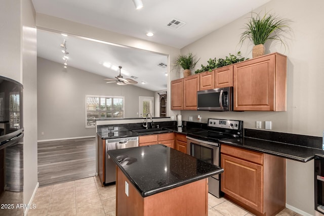 kitchen featuring a kitchen island, appliances with stainless steel finishes, sink, dark stone counters, and kitchen peninsula