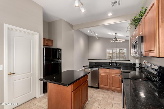 kitchen with sink, light tile patterned floors, dark stone countertops, stainless steel appliances, and a center island