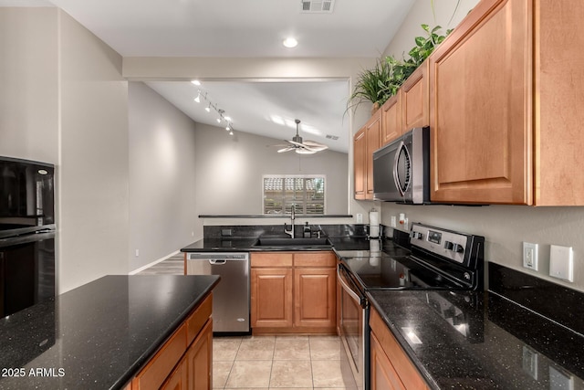 kitchen with light tile patterned flooring, lofted ceiling, sink, dark stone countertops, and stainless steel appliances