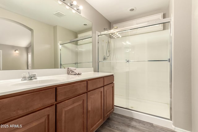 bathroom featuring an enclosed shower, vanity, and wood-type flooring