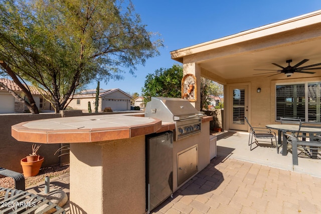 view of patio / terrace featuring ceiling fan, a grill, and exterior kitchen