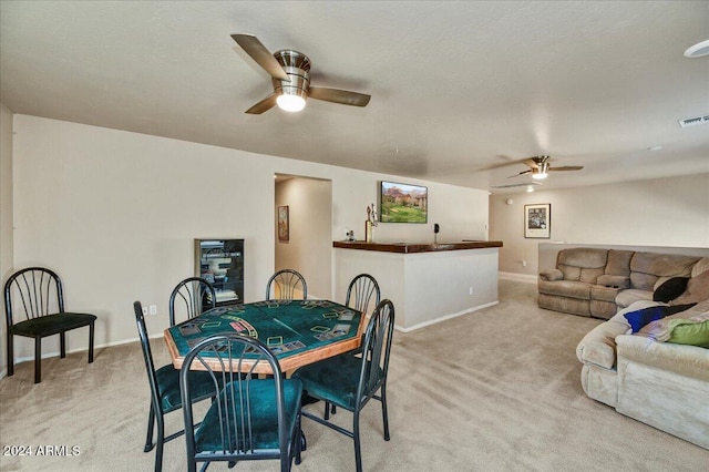 carpeted dining space with ceiling fan