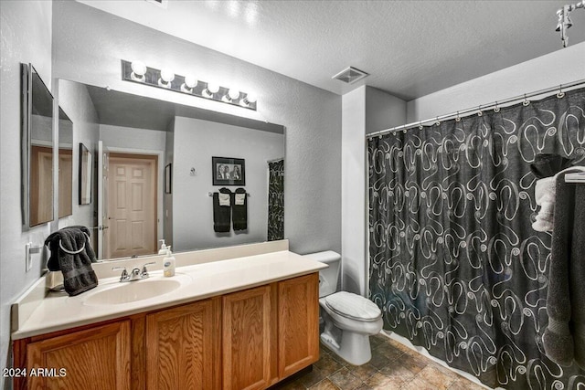 bathroom with vanity, a textured ceiling, and toilet